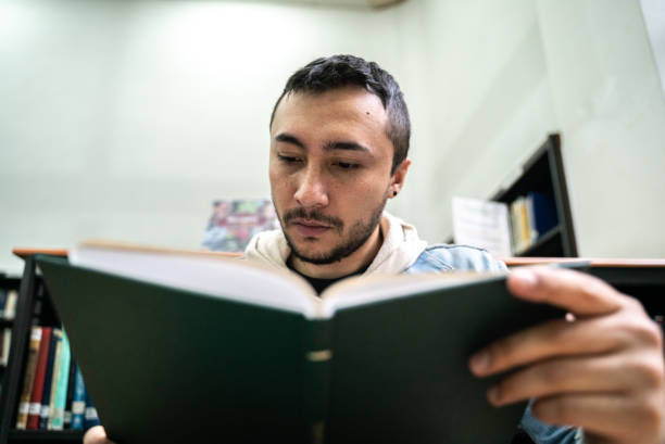 istock Young student reading a book in the library at the university 1494588909