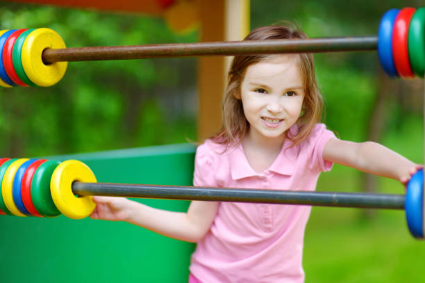 istock Little girl having fun at a playground with a giant abacus 1494589048