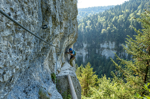 Wide angle view of sporty man climbing in summer on Via Ferrata in France