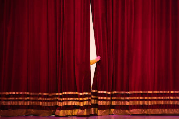 istock Human hand between red velvet theatre curtain 1494590188