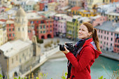Young female tourist enjoying the view of Vernazza, one of the five centuries-old villages of Cinque Terre, located on rugged northwest coast of Italian Riviera, Italy.