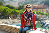 Young female tourist enjoying the view of small yachts and fishing boats in marina of Lerici town, located in the province of La Spezia in Liguria, Italy.