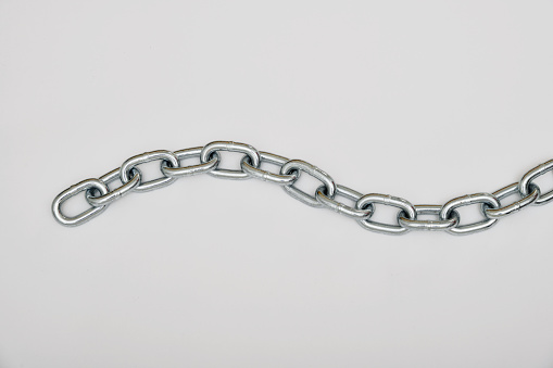 Top view of piece of strong silver metal chain placed on gray background