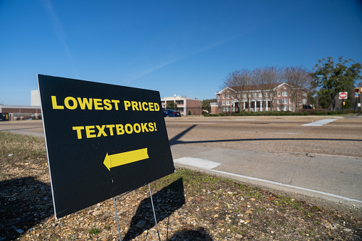 A roadside sign advertising low priced textbooks for students.