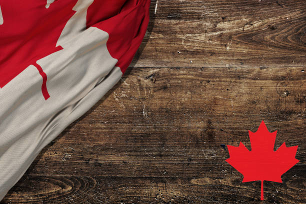 istock Canadian red and white maple leaf flag against dark wood rustic background for Canada Day, July 1, celebration and national holidays. 1494596244