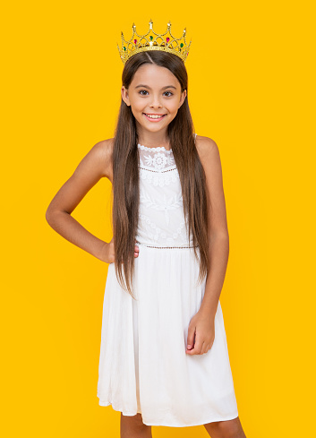 happy teen girl in crown on yellow background.