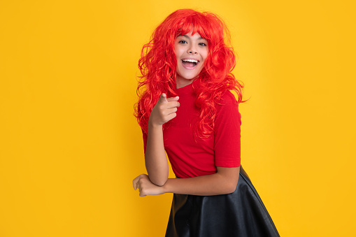 amazed teen kid with red long hair on yellow background.