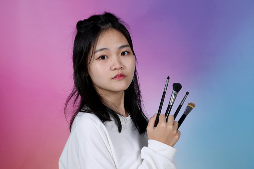 Portrait of an Asian young woman holding makeup brush