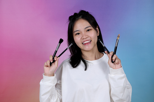 Portrait of an Asian young woman holding makeup brush