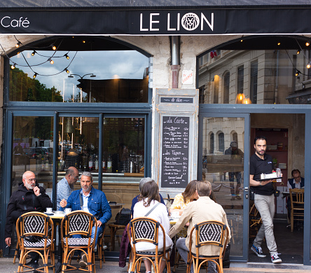Lyon France: As a waiter works, customers sit chatting at Le Lion Bar on Quai Saint-Antoine in the morning.
