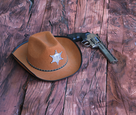 sheriff hat and revolver on wooden background