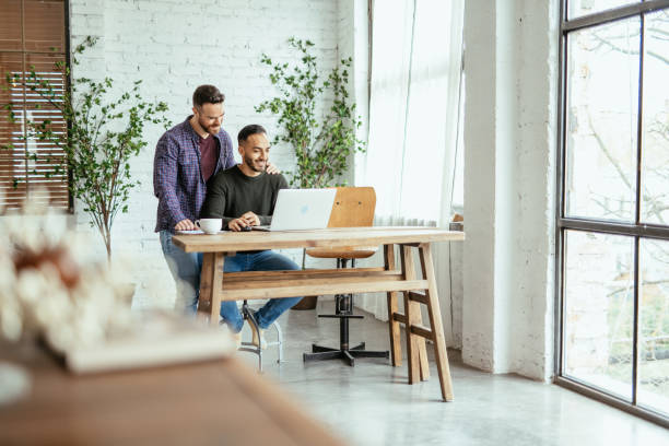 istock Multi ethnic gay couple at home, working remotely on laptop 1494608112