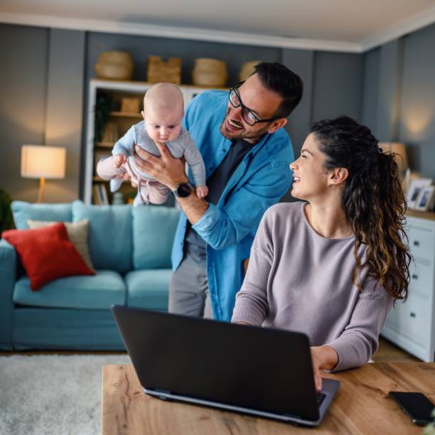 istock Family with a baby at home, mom using a laptop. 1494614556