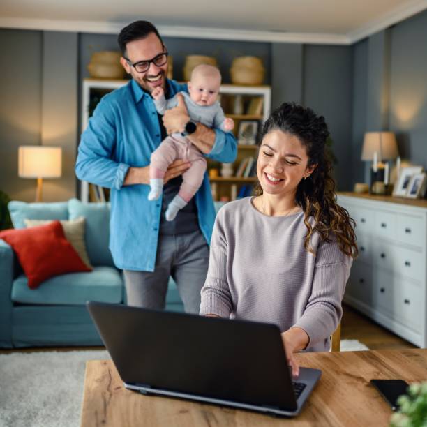 istock Family with a baby at home, mom using a laptop. 1494614887