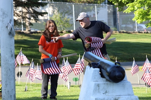 Woodbrook Cemetery, Woburn, MA. May 27, 2023. Volunteers placing an American Flag on the grave of a Military Veteran for Memorial Day.