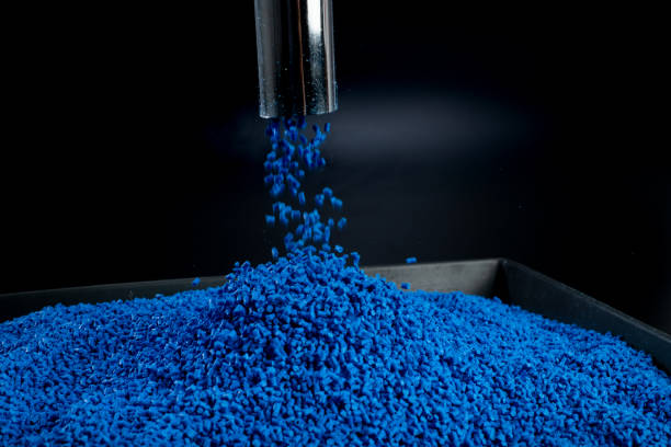 istock Shot of blue polymer granules falling through a metal pipe on a black tray with black background 1494617755