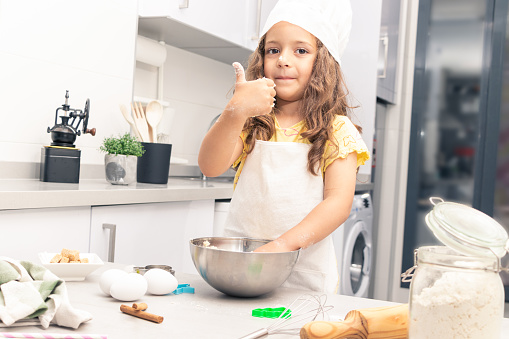 pastry girl with cap in the kitchen kneading cookie dough, enjoying pastry making