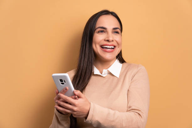 istock woman smiling and holding mobile phone 1494623003