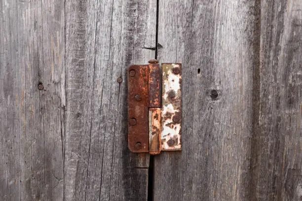 Photo of Old rusty hinge on a wooden door. Old rustic background