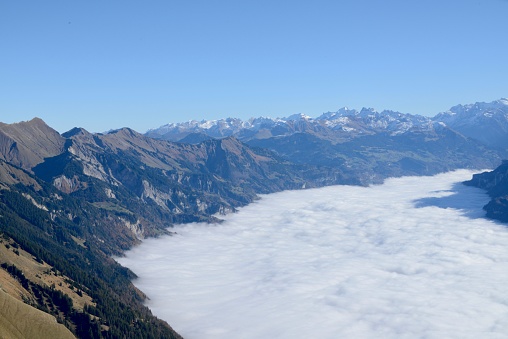 The wispy clouds cascading down the rugged slopes of a mountain range at Bernese Highlands