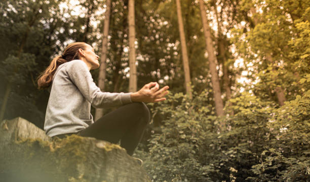 istock Woman meditating in green nature forest setting. 1494624522