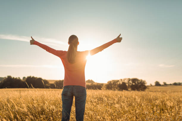 istock Young female feeling grateful, joyful standing outdoors in the sunrise. 1494624970