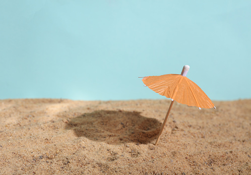 Miniature ubrella on the sand. Beach holiday, summer time