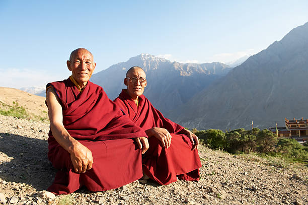 Two Indian Tibetan monks are sitting on a mountain Two Indian tibetan old monks lama in red color clothing sitting in front of mountains lama religious occupation stock pictures, royalty-free photos & images