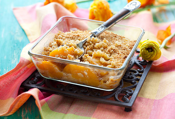A bowl of peach crumble on a black plate Delicious peach crumble cobbler dessert stock pictures, royalty-free photos & images