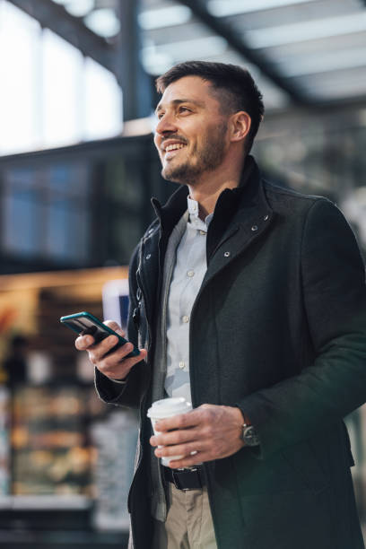 istock Happy Businessman Using A Mobile Phone At Bus Station 1494628534