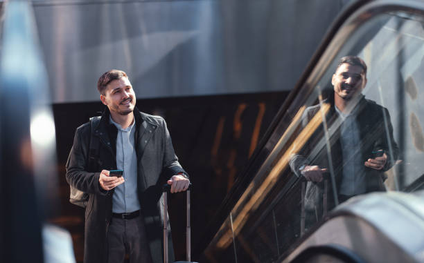 istock Happy Businessman Using A Mobile Phone While Riding Escalator At Subway Station 1494628591