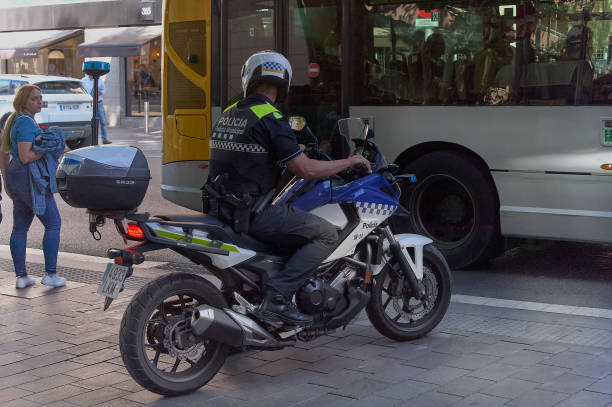 Gava municipal police biker riding his motorbike. Gava - May 30, 2023: Gava municipal police biker riding his motorbike, being watched by a citizen as a passenger bus passes by. police policewoman women spain stock pictures, royalty-free photos & images