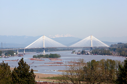 Stunning Port Mann Bridge in late afternoon. Taken from New Westminster BC. The Port Mann Bridge is a 10 lane cable-stayed bridge. Crosses over the Fraser River from Surrey to Coquitlam. Looking East. Snow on mountain in background.