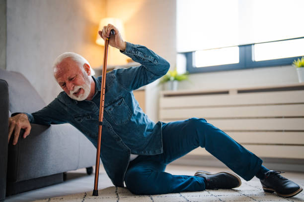 älterer mann, der mit beißer im wohnzimmer zu hause auf den boden fällt. - falling senior adult people one person stock-fotos und bilder