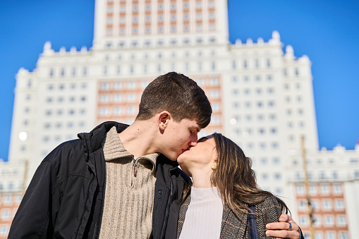 young engaged couple kissing in the streets of madrid