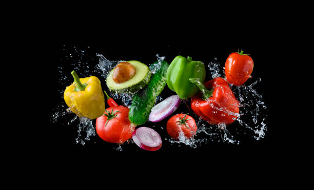 Fresh organic vegetables in water splash, isolated on black background.