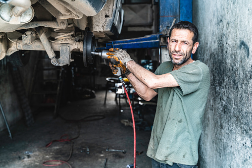 image of auto industry master doing car maintenance and repair. auto mechanic in oil and dirt. Shot with a full-frame camera in daylight.