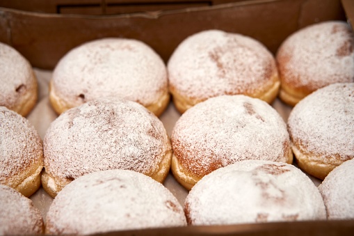 A close-up image of several donuts stacked in a colorful box