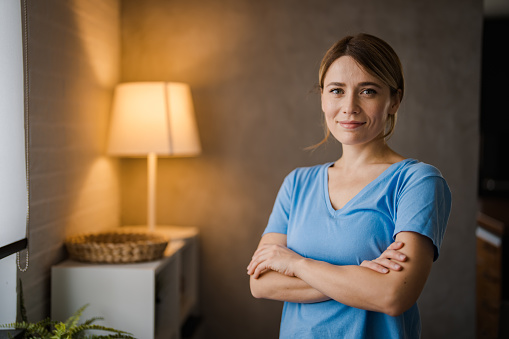 Portrait of smiling woman looking at camera. Successful middle aged woman at home smiling. Beautiful mid adult lady in casual with long brown hair enjoying. Portrait of beautiful girl smiling