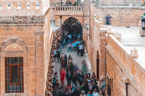A crowded street view in Midyat district of Mardin province, which is a historical city. The tourists were photographed using the long exposure technique while visiting the stone mansions.Taken with a full-frame camera in daylight from a high angle.