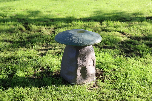 Stone mushroom seat on grass in sunshine