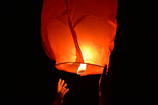 A red colored lantern flying in dark sky during Diwali.