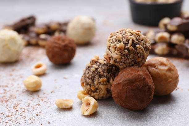istock Tasty chocolate candies and nuts on light grey table, closeup. Space for text 1494647291