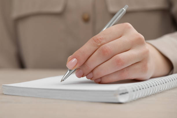 istock Woman writing in notebook at wooden table, closeup 1494649008