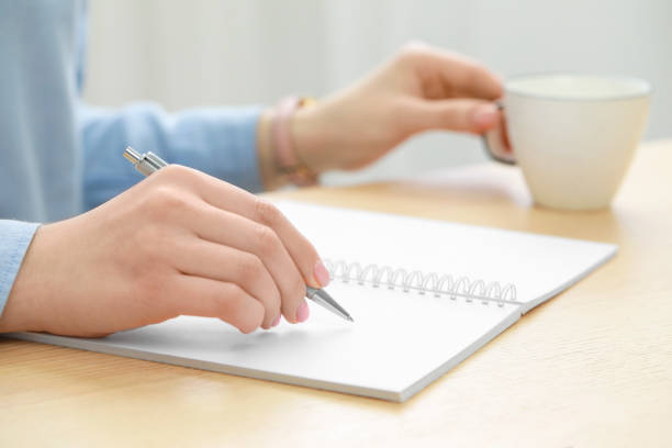 istock Woman writing in notebook at wooden table, closeup 1494649022