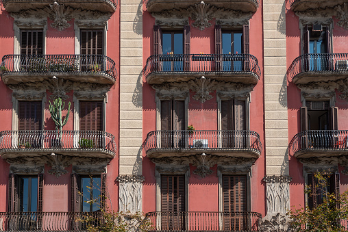 This is a color photograph of an old residential building with wrought iron details and wooden shutters by the windows in Paris, France.