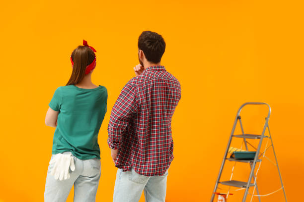 istock Designers looking at freshly painted orange wall, back view 1494650386