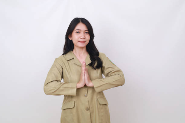 istock Friendly young indonesian government worker standing while showing welcome hand gesture 1494652343