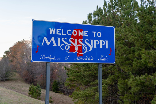 New Hope, MS - December 2020: A bright blue sign welcomes travelers to the state of Mississippi on the border of Alabama.
