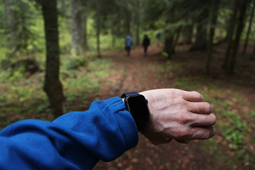 Man checking his smart watch in the forest